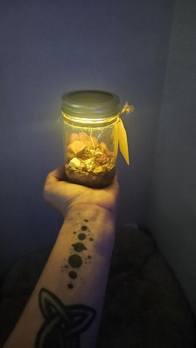 Small lantern jar glowing in a hand at night